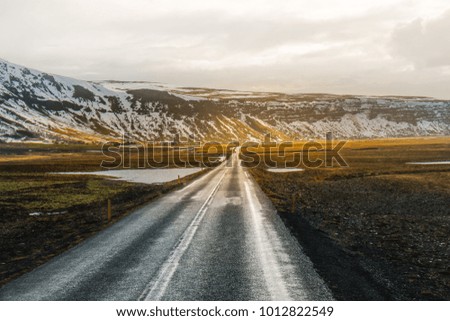 Beautiful View and winter landscape picture of Iceland's golden circle road during the sunset with the snow-capped mountain as a background and the road asphalt as a foreground.