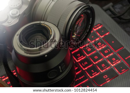 Mirrorless camera and lens against red glow keyboard background