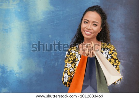 Smiling Vietnamese woman holding packages with her purchases