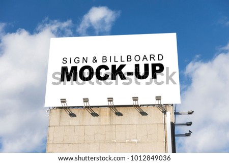 The mock up of front view the large billboard on top of  the building with clipping path , blank white space for advertisement outdoors on the roof with spotlight on blue sky