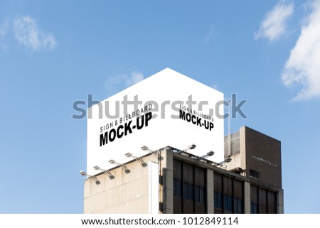 The mock up of the large billboard over the building with clipping path, blank white space for advertisement outdoors on the roof with spotlight and blue sky background