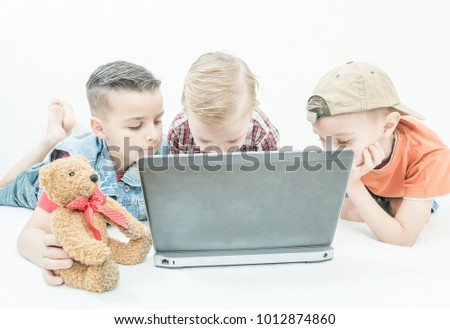 three cute little happy kids, sitting on a laptop and watching a cartoon, close up portrait of children isolated on a white background, lifestyle concept