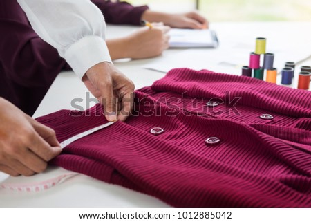 two young women working as fashion designers and drawing sketches and gets fabric advice at a custom tailor