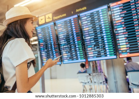 Asian teenage girl is using a smartphone to check flight at the international airport to travel on weekends. Royalty-Free Stock Photo #1012885303
