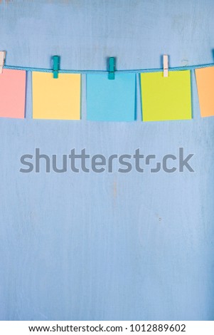 Five sheets of paper hang on a rope on a blue wooden background.