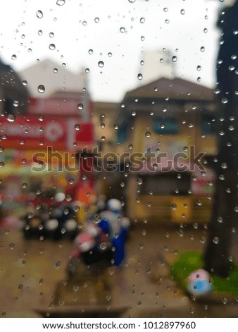 blurred rain drop on the glass window, building on street background.