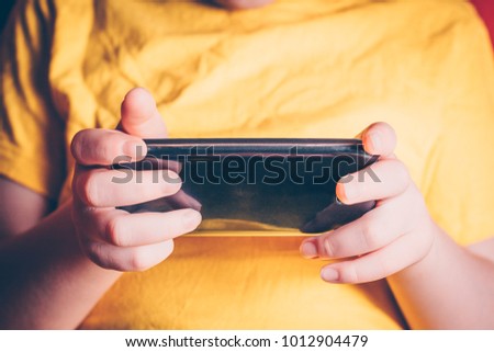 A child watches a closely movie on a smartphone