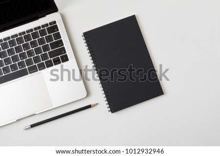 Top view desk with laptop closed black cover notebook and pencil on white desk background Royalty-Free Stock Photo #1012932946