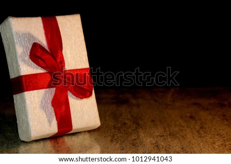 beautiful gift tied with a red ribbon on a black background