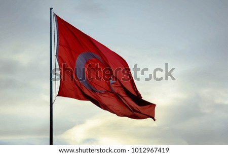 The Turkish flag flies on a background sky