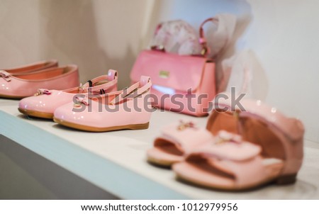 Peach colored Kids Shoes and Sandals arranged in the rack.