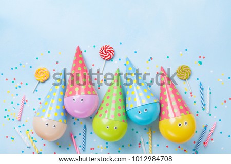 Birthday or party background. Funny balloons, candy and confetti on blue table top view. Flat lay. Invitation card. 