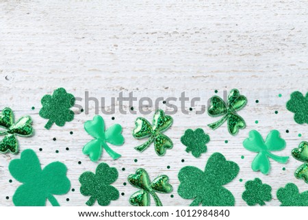 Saint Patricks Day background with green shamrock on white rustic board top view.