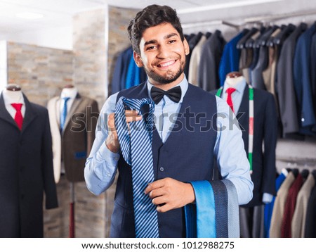 Buyer is picking up tie for waistcoat in men's shop.