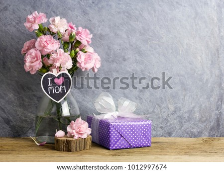 Happy mothers day concept of pink carnation flowers in bottle with i love mom letter on heart wood and violet  gift box Royalty-Free Stock Photo #1012997674
