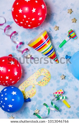 colorful carnival or party pattern of balloons, streamers and confetti on blue table. Flat lay style, birthday or carnival party greeting card.