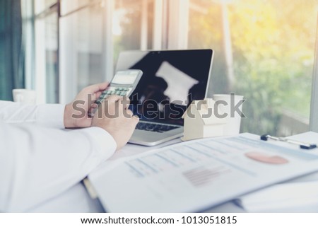 Business people use the computer laptop to calculate the interest on the loan, and the tax on a purchase-sale of real estate