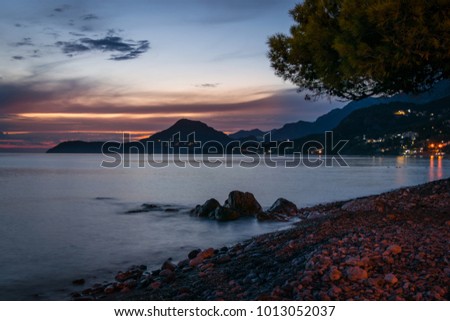 Beautiful sunset on the beach in Bar in Montenegro with long exposure effects in the sea.  Beach landscape with city lights in the background.  Royalty-Free Stock Photo #1013052037