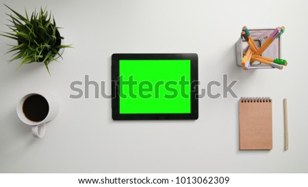 Man's fingers zooming in on the green touchscreen. A tablet is on the white table. View from the top. Close-up.