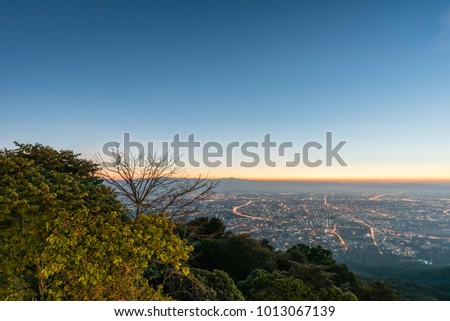 View of Chiang Mai city before sunrise with tree at foreground.