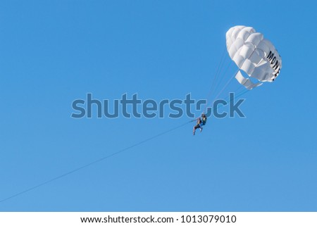 Two persons are gliding over the sea in the sunny day. Negative space made by blue sky and parachute.  Royalty-Free Stock Photo #1013079010