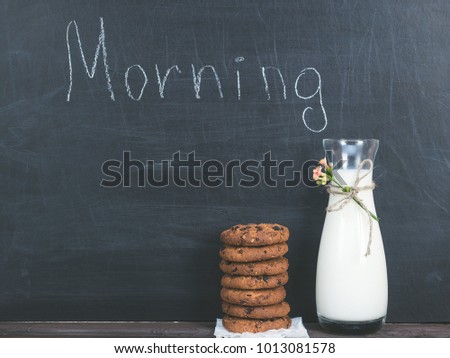 Jug of fresh milk and a fragrant cookies with chunks of chocolate, chalkboard with the inscription MORNING