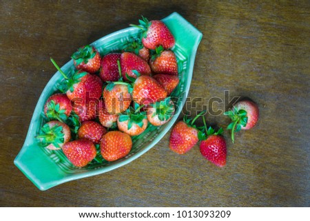 Strawberries in a boat bowl on rustic wood.