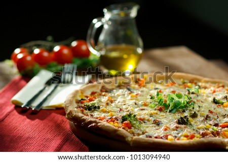 A composition of pizza with olive oil, cutlery and tomatoes.