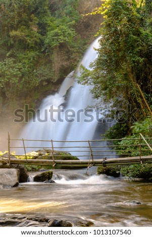 Waterfall flowing down the creeks, which a wooden bridge made out of bamboo used to walk across
