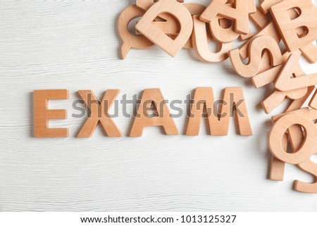 Word EXAM made of letters on wooden background