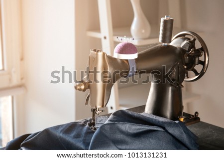 Old sewing machine with thread and fabric on table