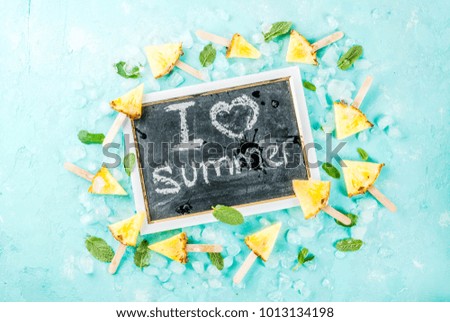 Slice pineapple popsicle sticks and mint leaves, on light blue background with ice, summer concept, copy space flat lay top view