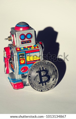 Vintage tin toy robot with bitcoin coin, cryptocurrency mining and investing concept