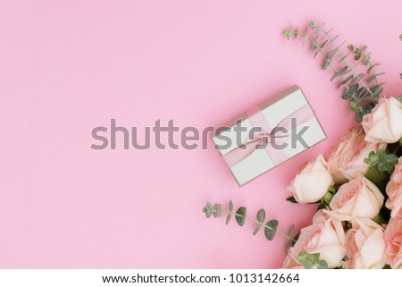 gift box and flowers on pink table from above, flat lay frame