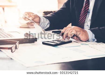 A business man using calculator for calculate expenses bills in his workplace. Business concept.