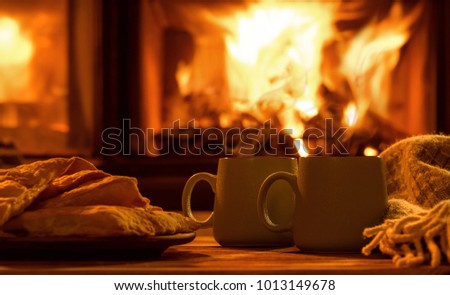 Steam from a cups with a hot cocoa on the fireplace background.  