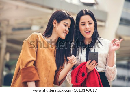 Two woman  holding smartphone  and searching  giving directions to hotel Traveler Journey concept