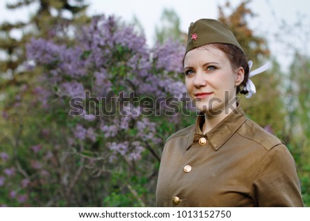 Pretty Soviet female soldier in the form of the Second World war against the background of lilac