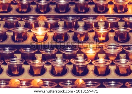 Rows of burning candles in glass cups in the church