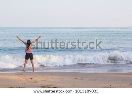 woman stretches her arms to the fresh air on the beach.