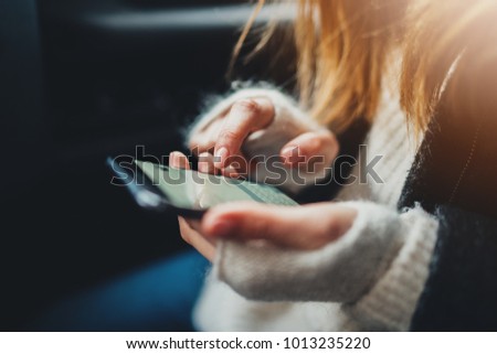 Closeup of female hands touching screen of smartphone device typing text message, hipster girl using an app for searching job via cellphone, woman using technology in car
