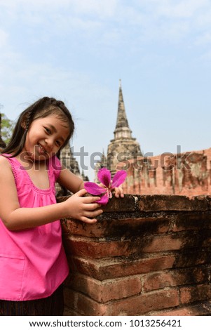 Cute little girl in Thai traditional dress.She smile and holding pink flower at Wat Phra sri Sanphet at Ayutthaya,Thailand