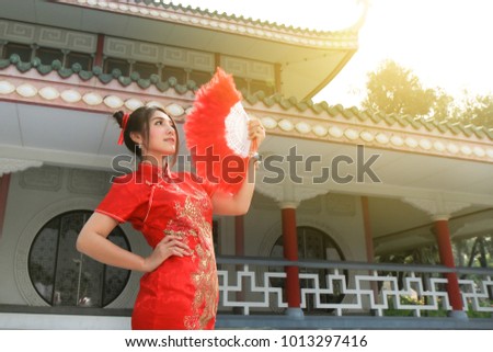 beautiful Chinese woman wearing  Cheongsam dress posting with red Chinese fan