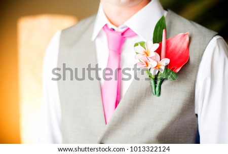 close-up picture on groom’s boutonnière. Beautiful frangipane boutonnière on grey vest