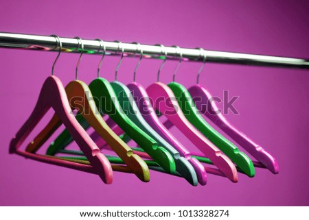 Wooden coat hangers on clothes rail and orange background
