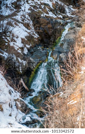 Frozen river in the Caucasus mountains. Vertical picture.