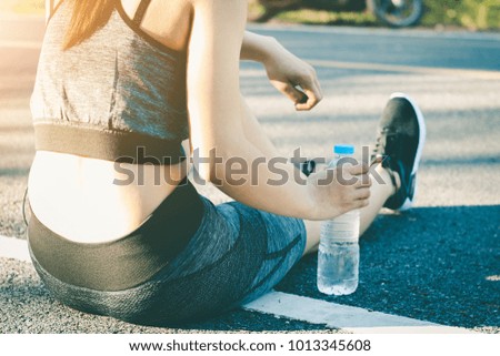 Young women stops drink water resting after running.