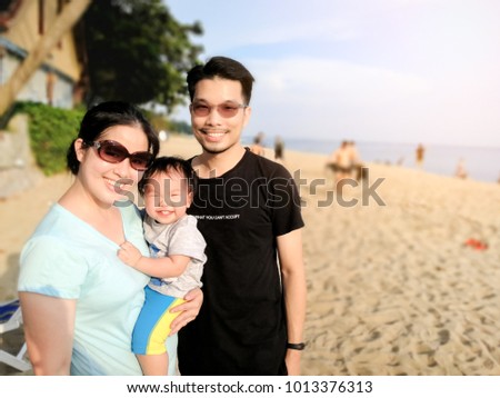 Happy asian family is having a good time at the beach in the summer. Baby is having a big smile with eyes blink.