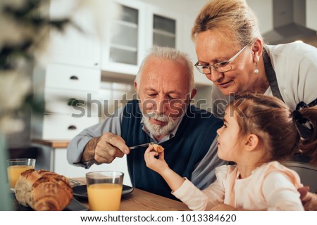 Grandparents having breakfast with their granddaughter Royalty-Free Stock Photo #1013384620