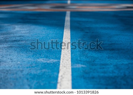 Abstract, blue background of newly made outdoor basketball court in park. Visible asphalt texture, freshly painted lines.